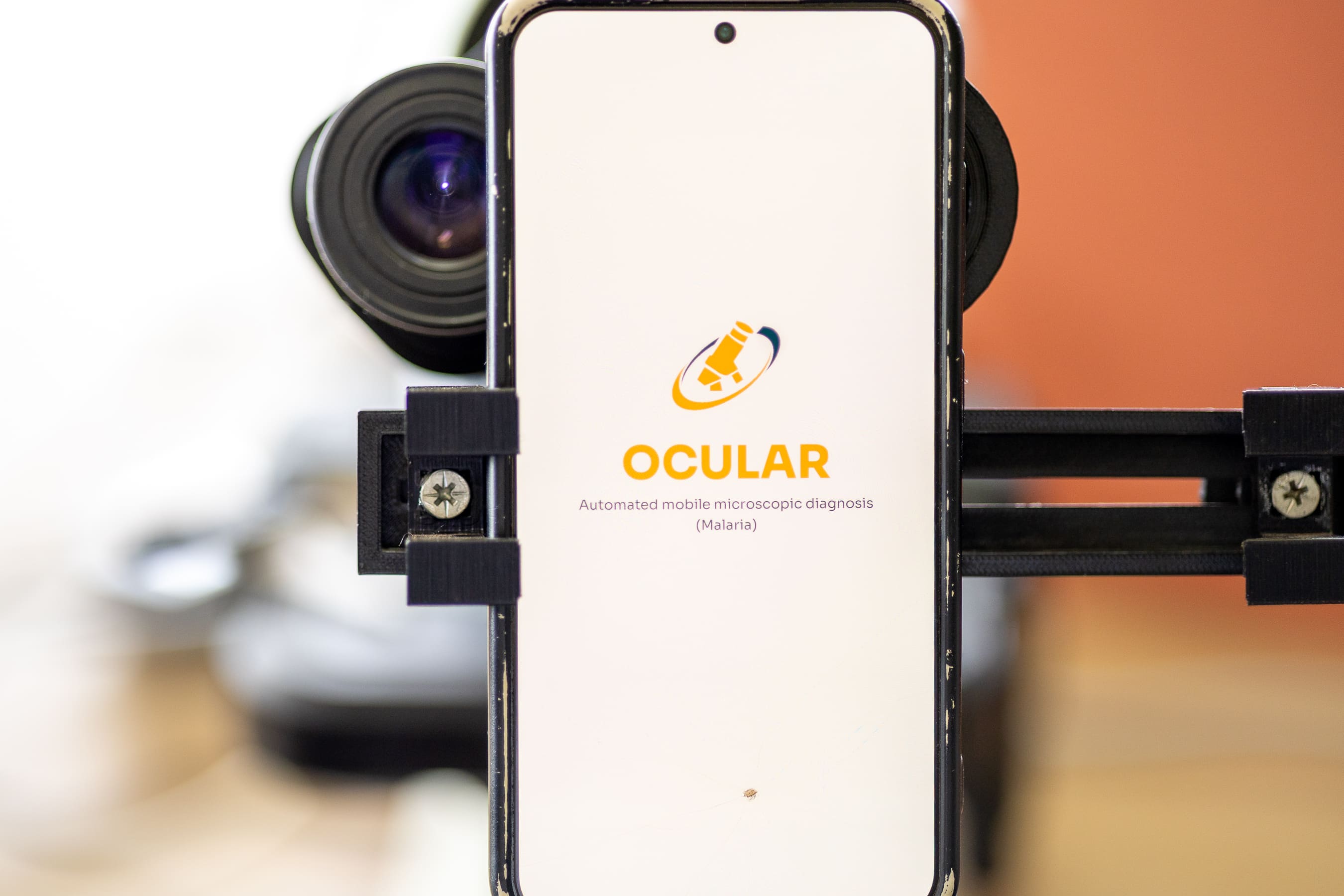 A researcher aligning a smartphone with a microscope eyepiece